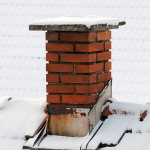 a masonry chimney surrounded by a snowy roof