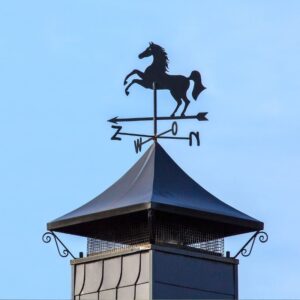 a triangle chimney cap with a weather vane on top with horse decor